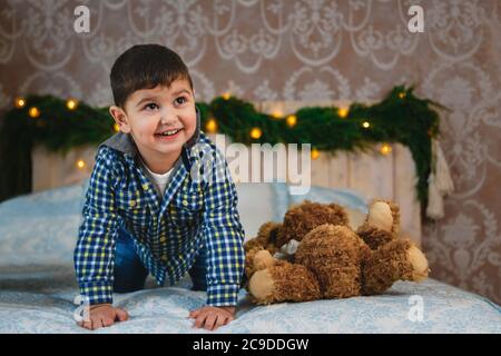 Weihnachtsporträt von glücklich lächelnd schönen kleinen Jungen spielend auf Bett mit Geschenk. Winterurlaub Weihnachten und Neujahr Konzept Stockfoto