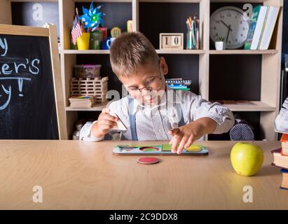 Grundschule. Talentiertes Kind. Lehrertag. Schulkinder. Zurück zur Schule. Kid ist das Lernen in der Klasse auf dem Hintergrund der Tafel.Pädagogische Spiele a Stockfoto