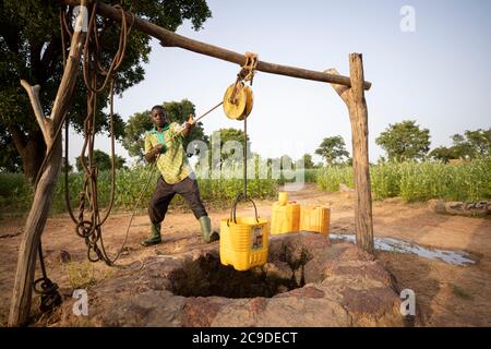 Ein Junge bezieht Wasser aus einem Brunnen in der Provinz Mouhoun, Burkina Faso, Westafrika. Stockfoto