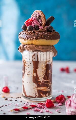 Schokoladenverwöhnendes Frosting exreme Milchshake mit Donut und Süßigkeiten. Crazy Freakshake Food Trend. Speicherplatz kopieren Stockfoto