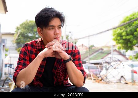 Junge gutaussehende asiatische Hipster Mann in den Straßen im Freien Stockfoto