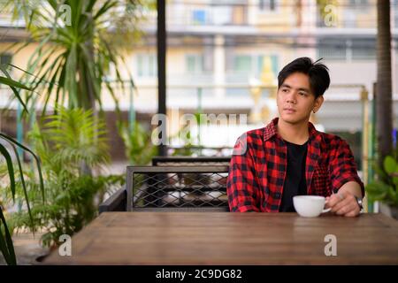Junger hübscher asiatischer Hipster-Mann im Café Stockfoto
