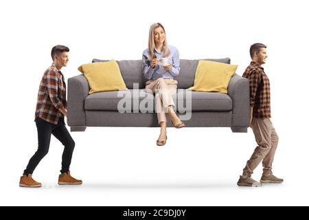 Junge Frau mit einer Tasse Kaffee auf einem Sofa sitzen und zwei Jungs tragen das Sofa isoliert auf weißem Hintergrund Stockfoto