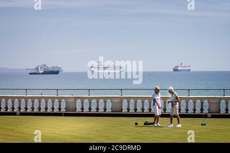 Paar reife Damen spielen Schalen vor der Sammlung von großen Kreuzfahrtschiffen in Weymouth Bay wegen Coronavirus - in Weymouth, Dorset, Stockfoto