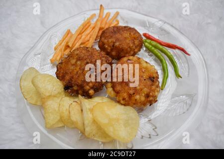 Indan Fasten upawas Fast-Diät-Essen Küche Artikel Sabudana wada serviert mit grünen und roten Chili auf dem Teller. Beliebte Upwas-Lebensmittel aus Indien gegessen Dur Stockfoto