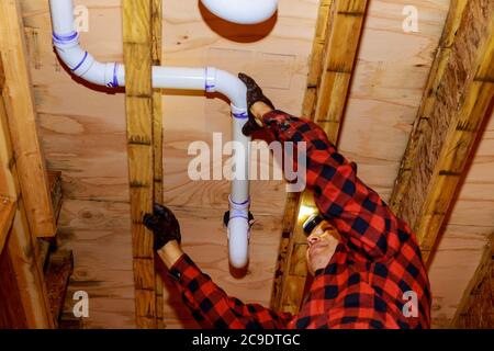 Arbeiter sind Abwasser Toilettenrohre mit PVC-Verbindungen ermöglicht die Spaltung der machen PVC-Rohr aus der anderen Seite des Gebäudedeckenbalkenhaus. Stockfoto