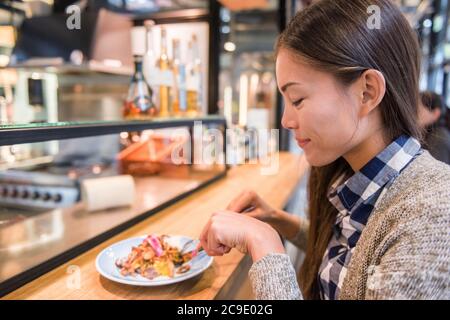 Frau, die im dänischen Restaurant isst, das traditionelle, smorrebrod offene Sandwich am Marktstand. Fröhlicher asiatischer Tourist, der typische Gerichte probiert Stockfoto