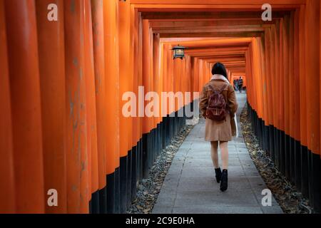 Eine asiatische Frau mit Rucksackwandern und Sightseeing am berühmten Reiseziel Fushimi Inari Schrein in Kyoto, Japan. Japan Tourismus, Natur Leben Stockfoto