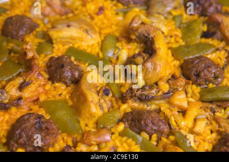 Detail einer frisch zubereiteten Reispaella mit Fleisch, Gemüse und Fleischbällchen Stockfoto