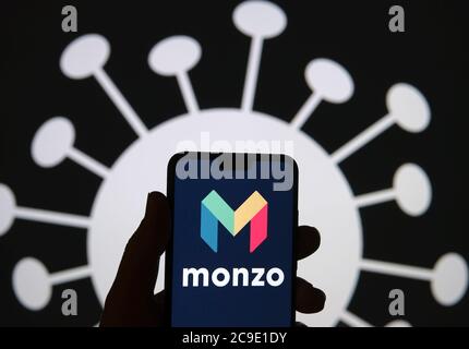 Stone / Großbritannien - Juli 30 2020: Silhouette des Smartphones mit Monzo Bank Logo auf dem Bildschirm und COVID-19 Form auf dem unscharfen Hintergrund. Monzo Stockfoto