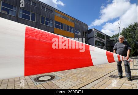 Rostock, Deutschland. Juli 2020. John Kasper, Hausmeister am Reutershagen Gymnasium, hält eine flatternde Band auf dem Schulhof, um die verschiedenen Schülergruppen in den Pausen zu trennen. Mecklenburg-Vorpommern wird am 03.08.2020 als erstes Bundesland wieder den regulären bundesweiten Schulbetrieb aufnehmen. Rund 150 Schüler werden nach den Sommerferien in ihren Schulen erwartet. Quelle: Bernd Wüstneck/dpa-Zentralbild/dpa/Alamy Live News Stockfoto