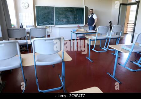 Rostock, Deutschland. Juli 2020. Markus Riemer, Direktor des Innerstädtischen Gymnasiums Rostock ISG, öffnet eine Tafel in einem Klassenzimmer mit der Corona-Anleitung: "Masken sind Pflicht! Gehen Sie nach rechts! Waschen Sie sich die Hände! Räume lüften!“. Mecklenburg-Vorpommern ist das erste Bundesland, das am 03.08.2020 den landesweiten Regelbetrieb der Schulen wieder aufnimmt. Rund 150 Schüler werden nach den Sommerferien in ihren Schulen erwartet. Quelle: Bernd Wüstneck/dpa-Zentralbild/dpa/Alamy Live News Stockfoto