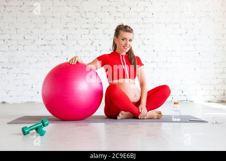 Lächelnde schwangere junge Frau mit einem ftigen Ball. Vorderansicht. Stockfoto