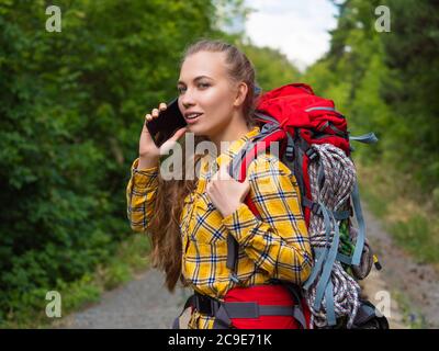 Junge Wanderfrau mit einem Smartphone im Wald. Ökotourismus Konzept. Stockfoto