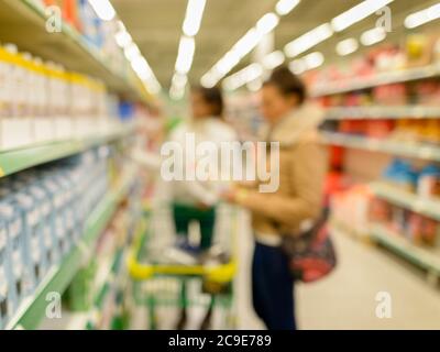 Verschwommene Kunden einkaufen für Lebensmittel im Supermarkt mit einer Vielzahl von Produkten in den Regalen geladen Stockfoto