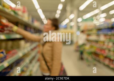 Verschwommene Kunden einkaufen für Lebensmittel im Supermarkt mit einer Vielzahl von Produkten in den Regalen geladen Stockfoto