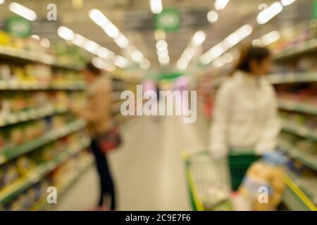 Verschwommene Kunden einkaufen für Lebensmittel im Supermarkt mit einer Vielzahl von Produkten in den Regalen geladen Stockfoto