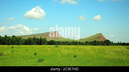 Zwei hohe Berge mit sanften Hängen vor dem Hintergrund einer flachen Steppe. Bergkette Truhen, Chakassien, Südsibirien, Russland. Stockfoto