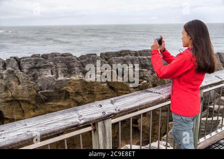 Neuseeland Reise-Tourist-Mädchen, das Smartphone-Bilder mit Handy-App auf Punakaiki Pancake Rocks. Frau im Paparoa National Park, Westküste Stockfoto