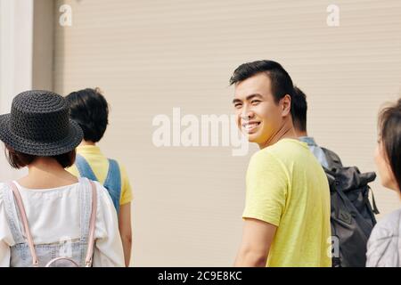 Positiver junger Asian Mann in einfachem gelbem T-Shirt, der zur Hochschule geht Stockfoto