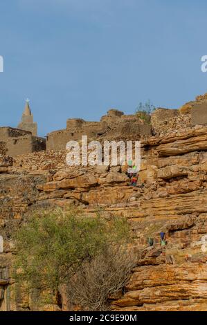 Frauen tragen Eimer mit Wasser auf dem Kopf bis zum Dorf Niogono Dogon im Gebiet Bandiagara, Land Dogon, Mali, Westafrika. Stockfoto