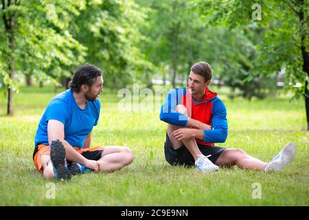 Zwei Freunde, die sich nach dem Training im öffentlichen Park ausruhen. Aktives und gesundes Lifestyle-Konzept. Selektiver Fokus. Stockfoto
