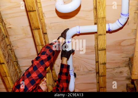 Arbeiter sind Abwasser Toilettenrohre mit PVC-Verbindungen ermöglicht die Spaltung der machen PVC-Rohr kommen aus der anderen Seite der GebäudeDecke Balkenhaus. Soft Focus Stockfoto