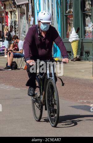 Cambridge, Großbritannien. Juli 2020. Ein Mann, der eine Gesichtsmaske als vorbeugende Maßnahme trägt, fährt mit dem Fahrrad auf der Straße. Die Menschen tragen eine Vielzahl von Gesichtsmasken im Freien in Cambridge, obwohl sie im Moment in Großbritannien nur auf öffentlichen Verkehrsmitteln und in Geschäften und öffentlichen Räumen vorgeschrieben sind. Kredit: SOPA Images Limited/Alamy Live Nachrichten Stockfoto