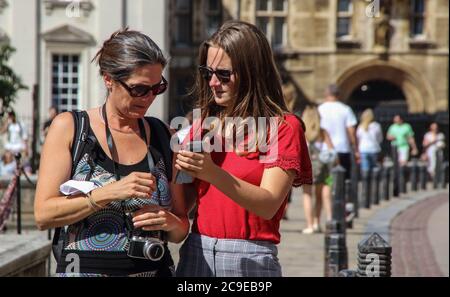 Cambridge, Großbritannien. Juli 2020. Zwei Damen vergleichen Fotos außerhalb des Kings College-Teils der Cambridge University an einem warmen Sommertag. Die Menschen entspannen sich während des warmen Sommerwetters, da die Temperatur in England voraussichtlich bis zum Wochenende 30 Grad Celsius erreichen wird. Kredit: SOPA Images Limited/Alamy Live Nachrichten Stockfoto