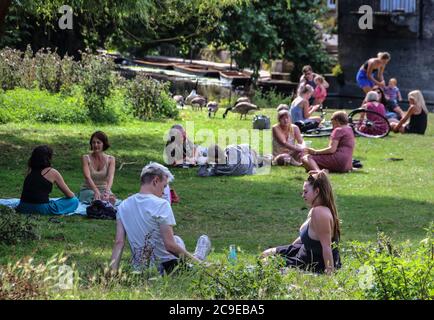 Cambridge, Großbritannien. Juli 2020. An einem warmen Sommertag entspannen sich die Menschen auf dem Rasen. Die Menschen entspannen sich während des warmen Sommerwetters, da die Temperatur in England voraussichtlich bis zum Wochenende 30 Grad Celsius erreichen wird. Kredit: SOPA Images Limited/Alamy Live Nachrichten Stockfoto
