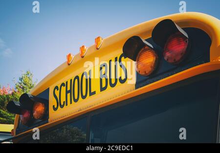 Oben ein gelber Schulbus mit Licht und Text. Nahaufnahme gegen blauen Himmel im Herbst. Zurück zur Schule Konzept. Speicherplatz kopieren. Stockfoto