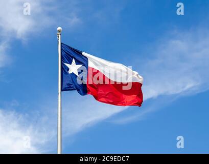 Texas State Flagge auf der Stange winkt im Flügel gegen blauen Himmel und weißen Wolken Stockfoto