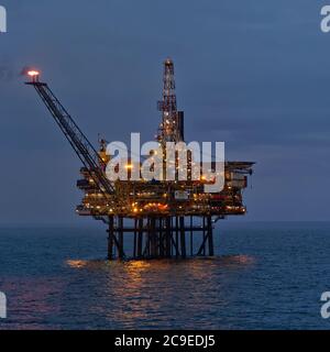 Die Gannet EINE Ölplattform in der Dämmerung eines Summers Abend in einer sehr ruhigen Nordnaht mit seinen Lichtern an, und Flare Stapel brennen. Stockfoto