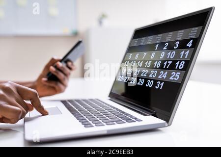 Frau, Die Sich Die Monatsübersicht Im Kalender Auf Laptop-Computer Ansieht Stockfoto