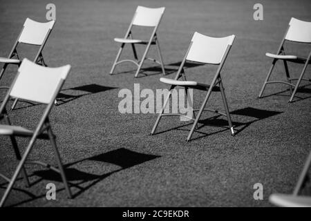 Stühle auseinander, um die soziale Distanz während der Covid-19 Ausbruch bei einem Outdoor-Event auf dem Rasen eines Stadions zu halten. Stockfoto