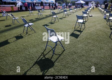 Stühle auseinander, um die soziale Distanz während der Covid-19 Ausbruch bei einem Outdoor-Event auf dem Rasen eines Stadions zu halten. Stockfoto