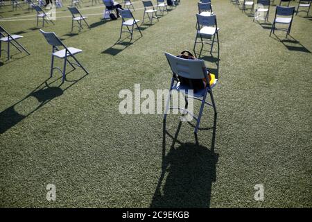 Chairs apart one from another to maintain the social distance during the Covid-19 outbreak at an outdoor event on the turf of a stadium. Stockfoto