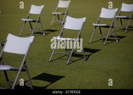Chairs apart one from another to maintain the social distance during the Covid-19 outbreak at an outdoor event on the turf of a stadium. Stockfoto
