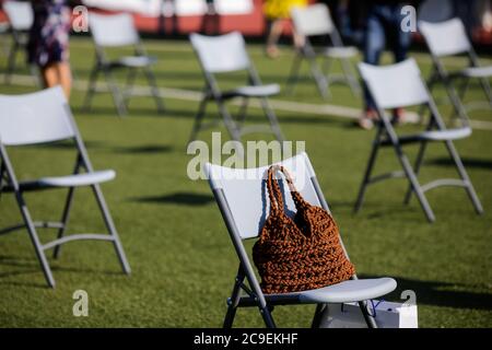 Stühle auseinander, um die soziale Distanz während der Covid-19 Ausbruch bei einem Outdoor-Event auf dem Rasen eines Stadions zu halten. Stockfoto