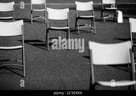 Stühle auseinander, um die soziale Distanz während der Covid-19 Ausbruch bei einem Outdoor-Event auf dem Rasen eines Stadions zu halten. Stockfoto
