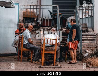 Albanische ältere Männer spielen Karten, unterhalten sich und lächeln in Vlore, Albanien Stockfoto