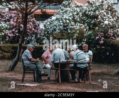 Albanische ältere Männer spielen Karten, unterhalten sich und lächeln in Vlore, Albanien Stockfoto