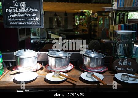 Die Anordnung der Buffet-Selbstbedienungsstation im lokalen südthailändischen Restaurant Thai Board bedeutet "wie oder Check-in erhalten Sie kostenlose Getränke" Stockfoto