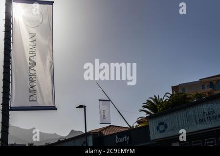 Hinterleuchtete Stoffbanner, die Luxusmarken auf Lampfosten vor dem Einkaufszentrum Plaza del Duque, Costa Adeje, Teneriffa, Kanarische Inseln, werben Stockfoto