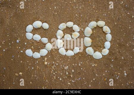 Inschrift auf dem Sand von Muscheln - seo, Camping, Tourismus Stockfoto