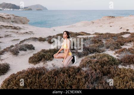 Frau am Strand trägt gelben Badeanzug Stockfoto