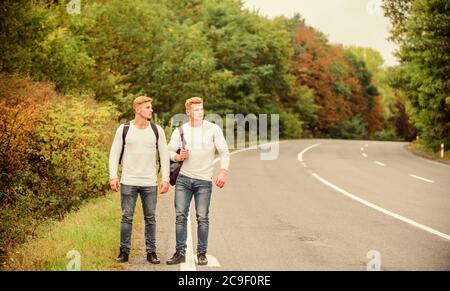 Gehen müssen. wanderlust Konzept. Wandern mit Freunden ist cool. gegangen, sich selbst zu finden. Reise trampen. Zwillinge zu Fuß entlang der Straße. Trampen auf leere Straße. Anreise per Trampen. Road Trip. Stockfoto