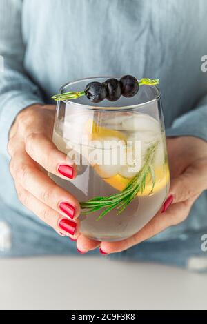 Nahaufnahme einer Frau Hände halten frische Limonade. Heidelbeere, Zitrone und Kraut in eiskaltem Glas. Stockfoto