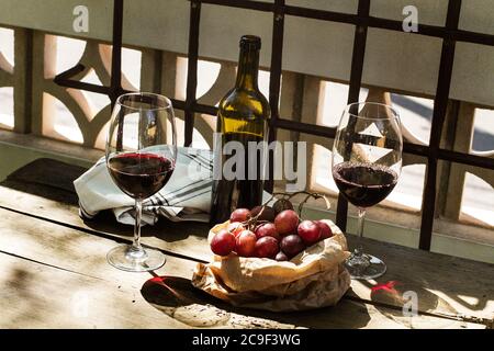 Eine Flasche und Gläser Rotwein auf einem rustikalen Tabelle in einem suny-Tag Stockfoto