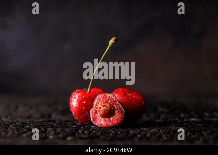 Stillleben von roten, saftigen Kirschen auf dunklem Grund. Kirschgruppe. Stockfoto